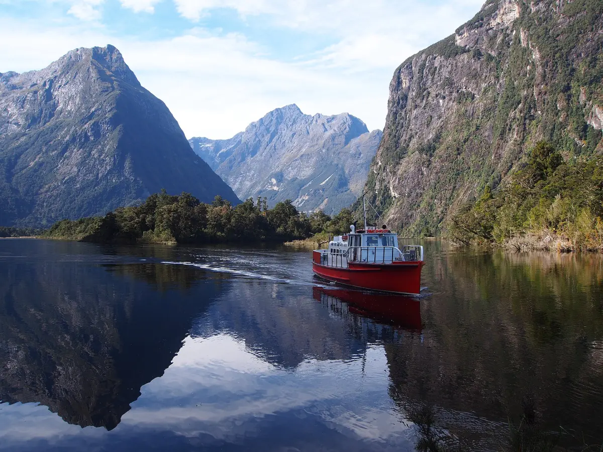 A boat crossing the still water of Milford Sound