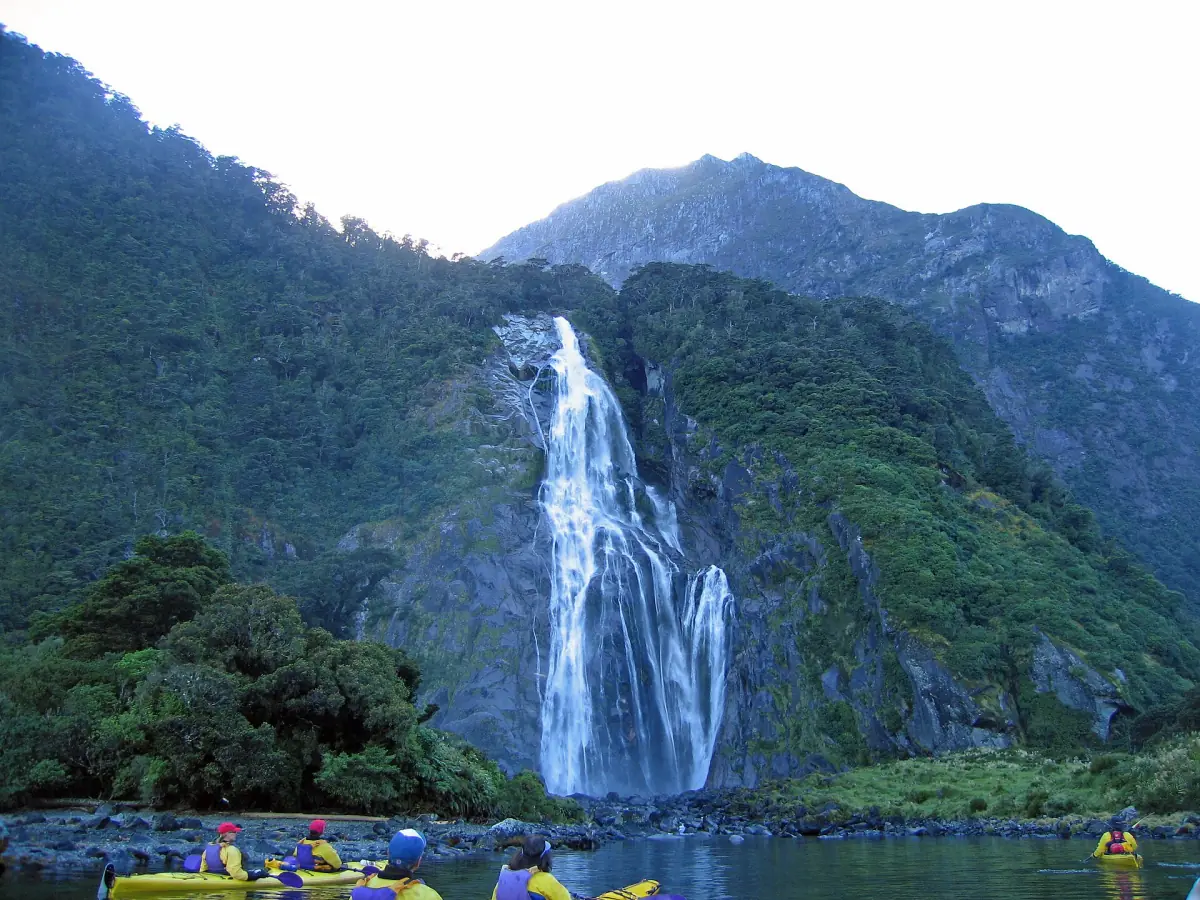 Kayaks below a waterfall in Milford Sound